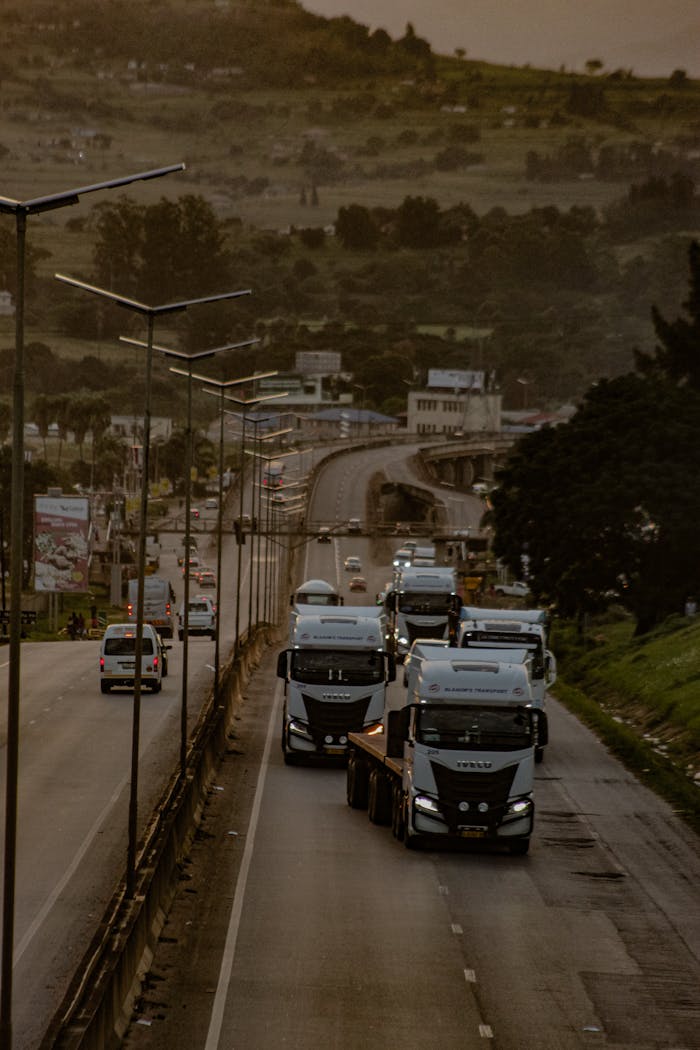Evening traffic with trucks on a highway in Matsapha, Eswatini, showcasing a scenic landscape.